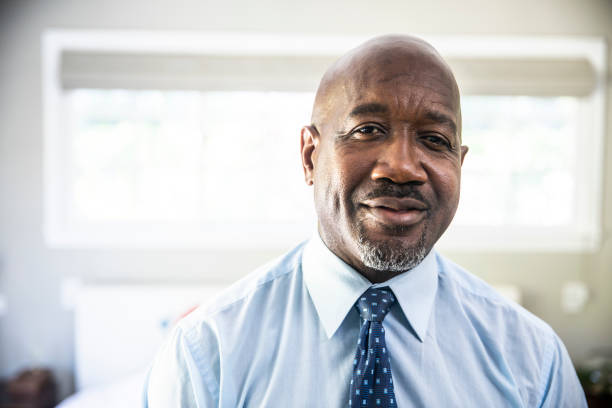 A mature black man looks out while standing on his porch